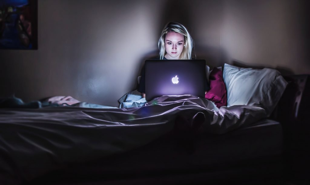 a girl in bed on her laptop