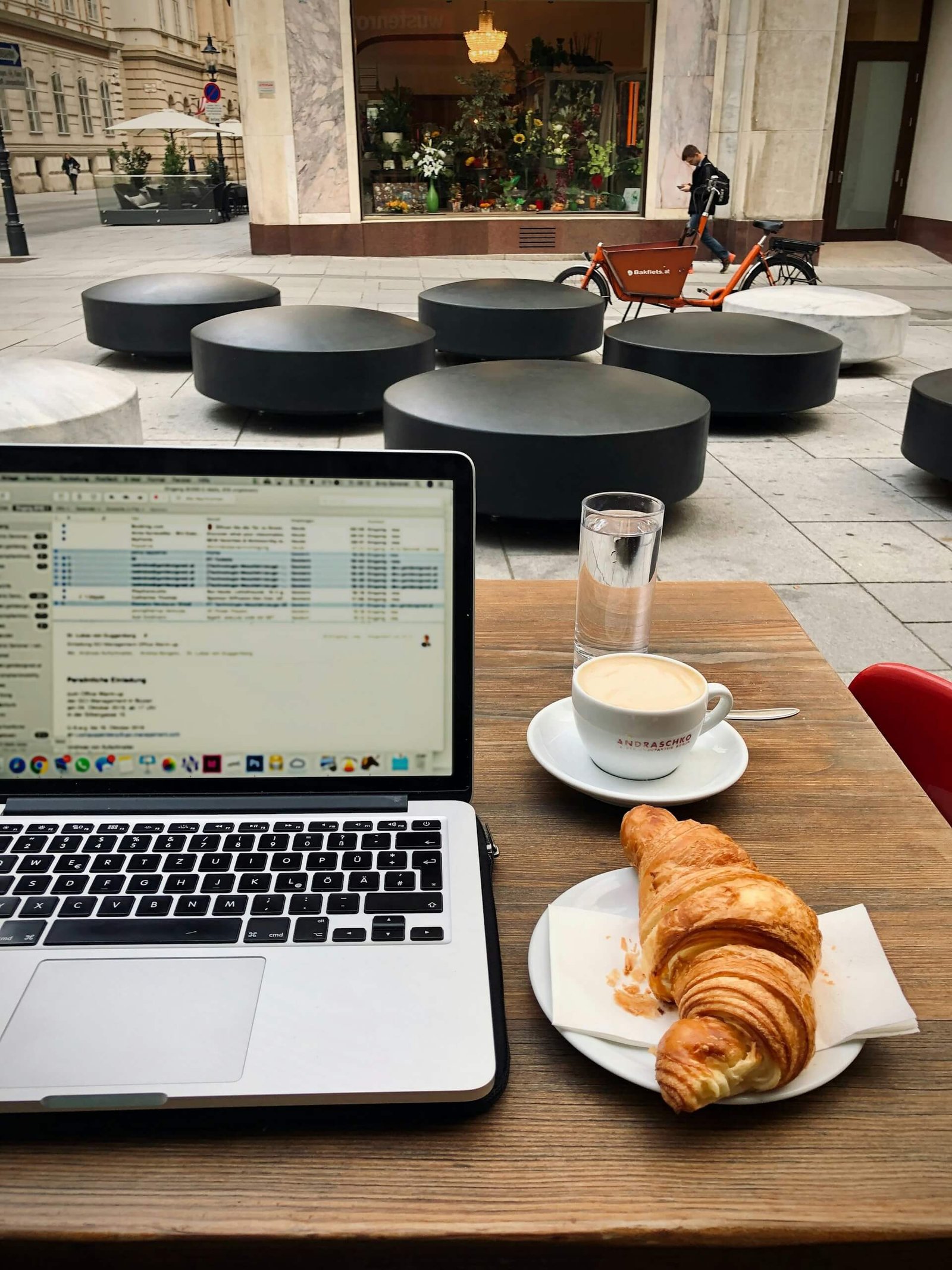 a laptop with a coffee and croissant