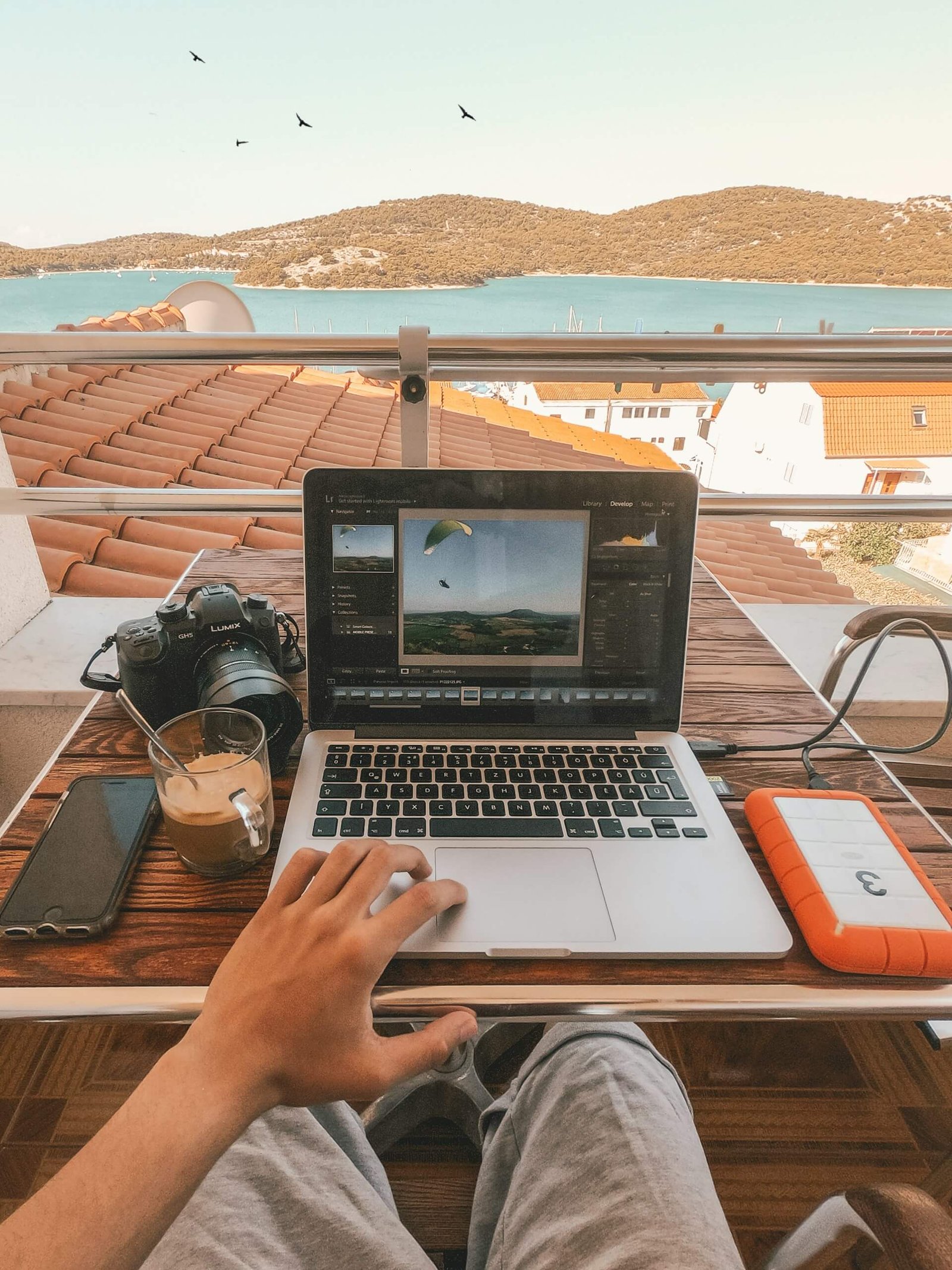 a laptop with a sunny sea view in the background