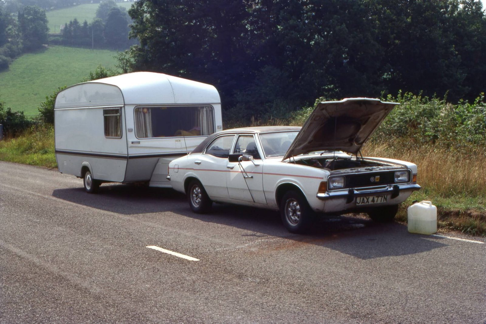 a car pulling a caravan broken down on the side of the road